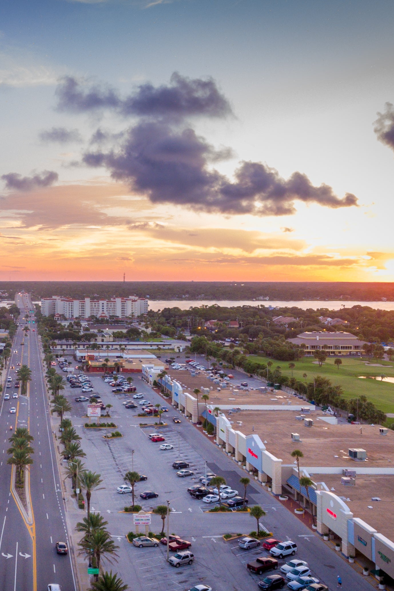Aerial view of buldings, roads, and parking lot at sunset.