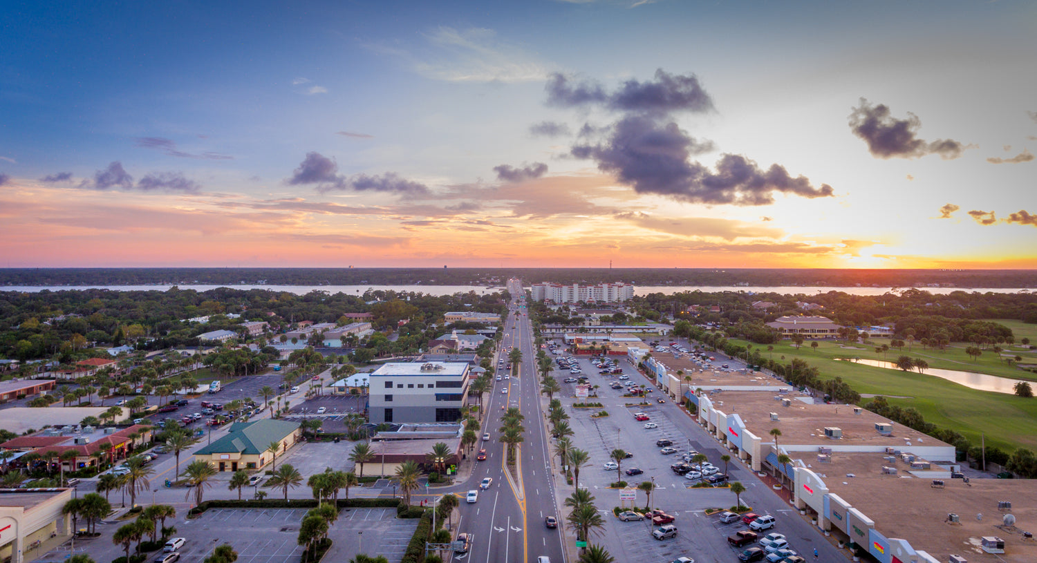 Aerial view of buldings, roads, and parking lot at sunset.