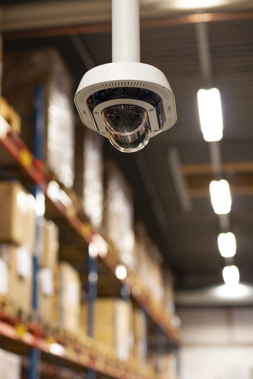 P4705 Camera hung from cieling in a warehouse corridor.